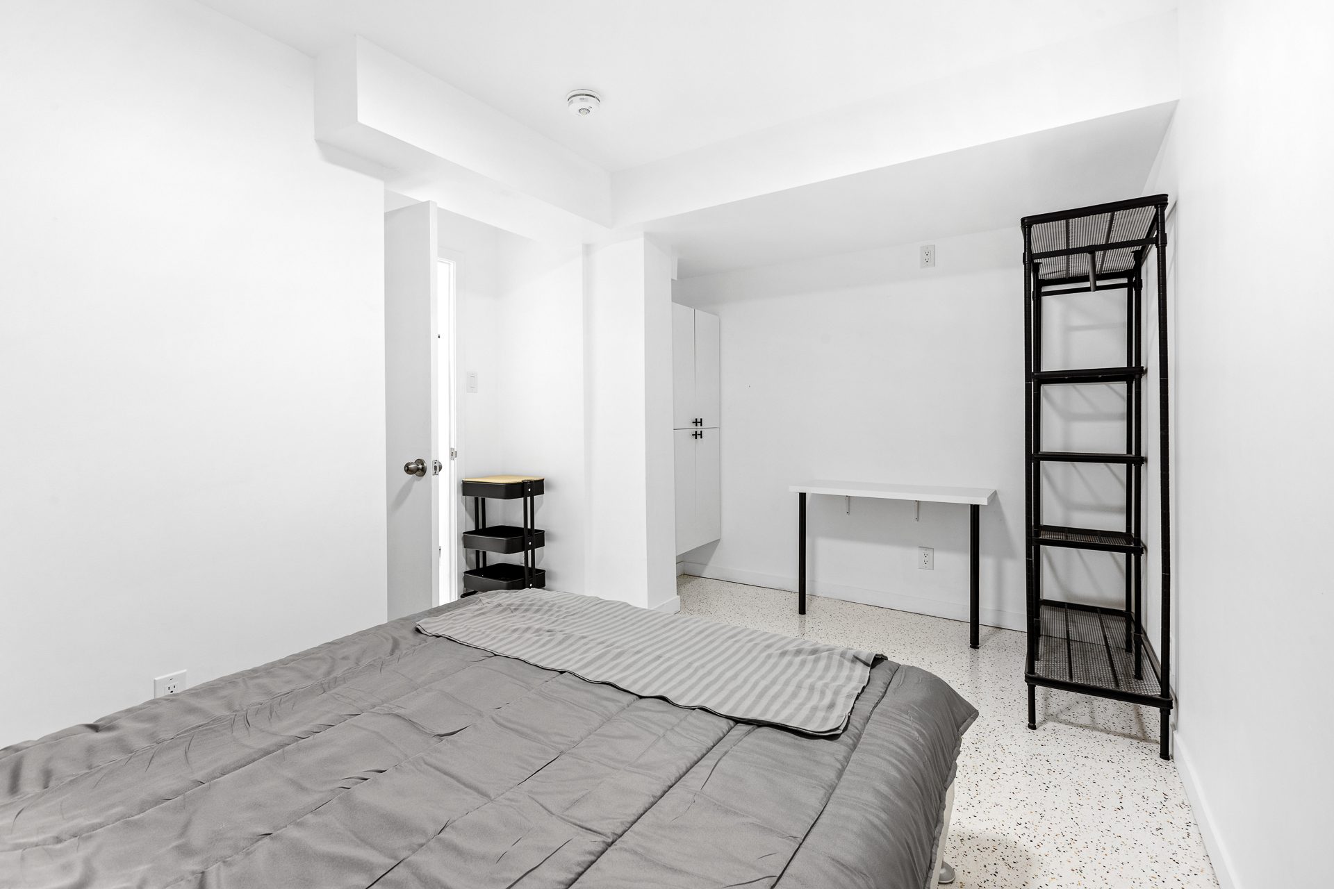 Unit 06 bedroom with bed, desk, and open shelving