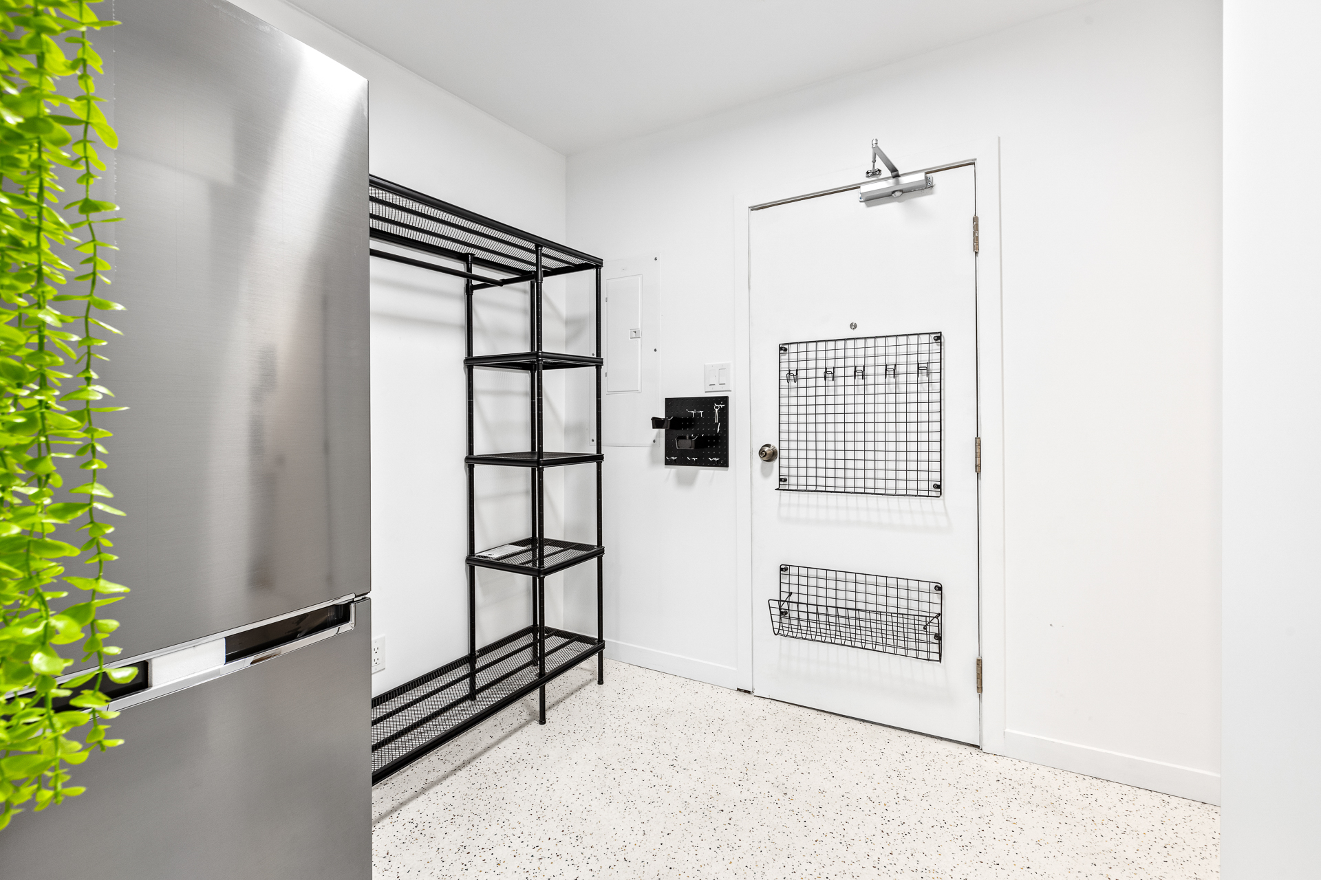 Unit 09 entry with refrigerator, storage shelving, and front door