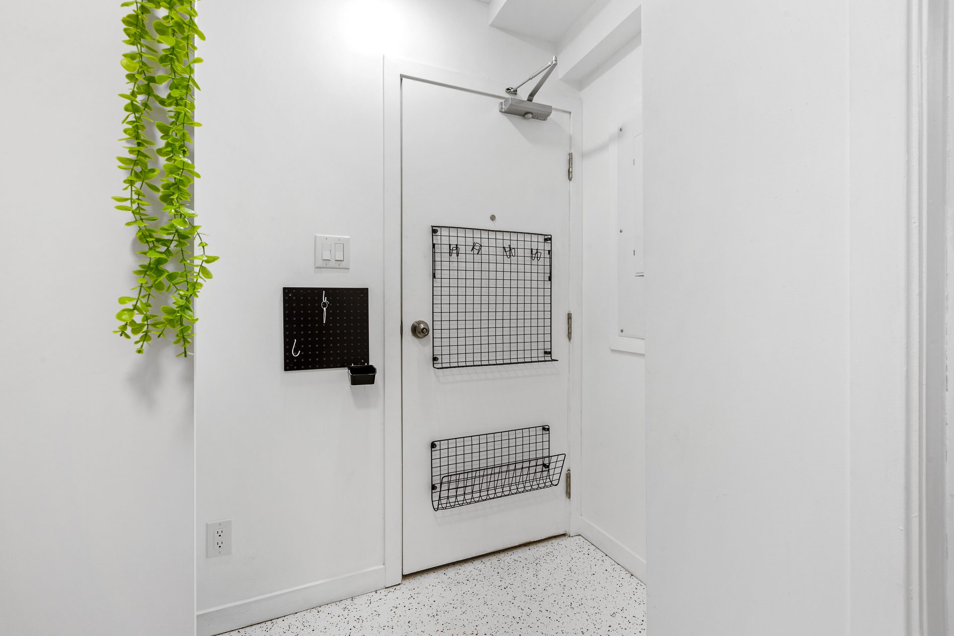 Unit 06 front door entry detail with hanging greenery and wall organizer