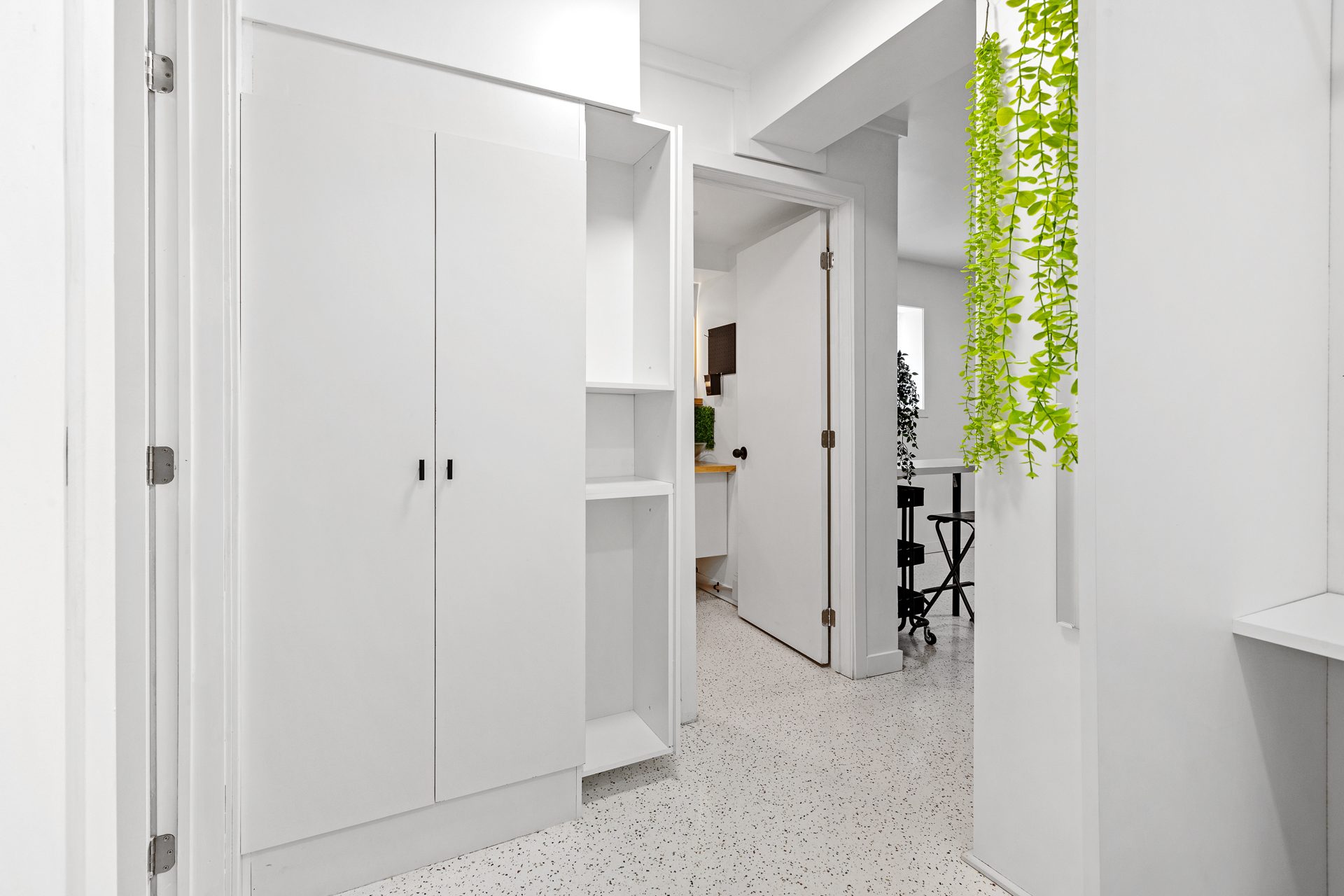 Unit 06 entry corridor with storage wall and view into the suite